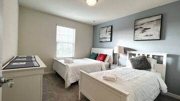 A hotel room with two single beds, a desk, and a window.