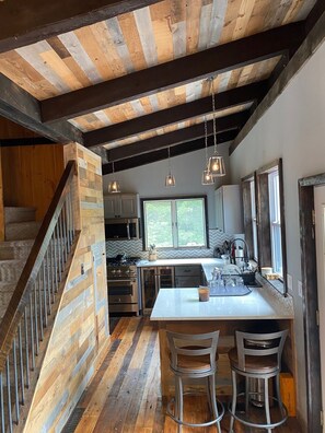 A modern kitchen with a central island, bar stools, and a herringbone-patterned backsplash. - Hermitage Club and Mt Snow (Wilmington)