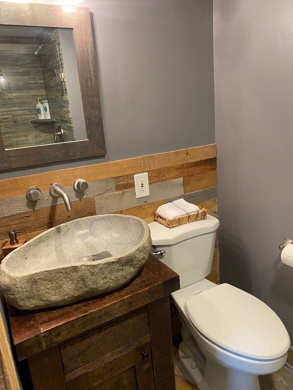 Ein Badezimmer mit einem Steinkonstruktion als Waschbecken, einer Holzwaschkommode und einer Toilette.