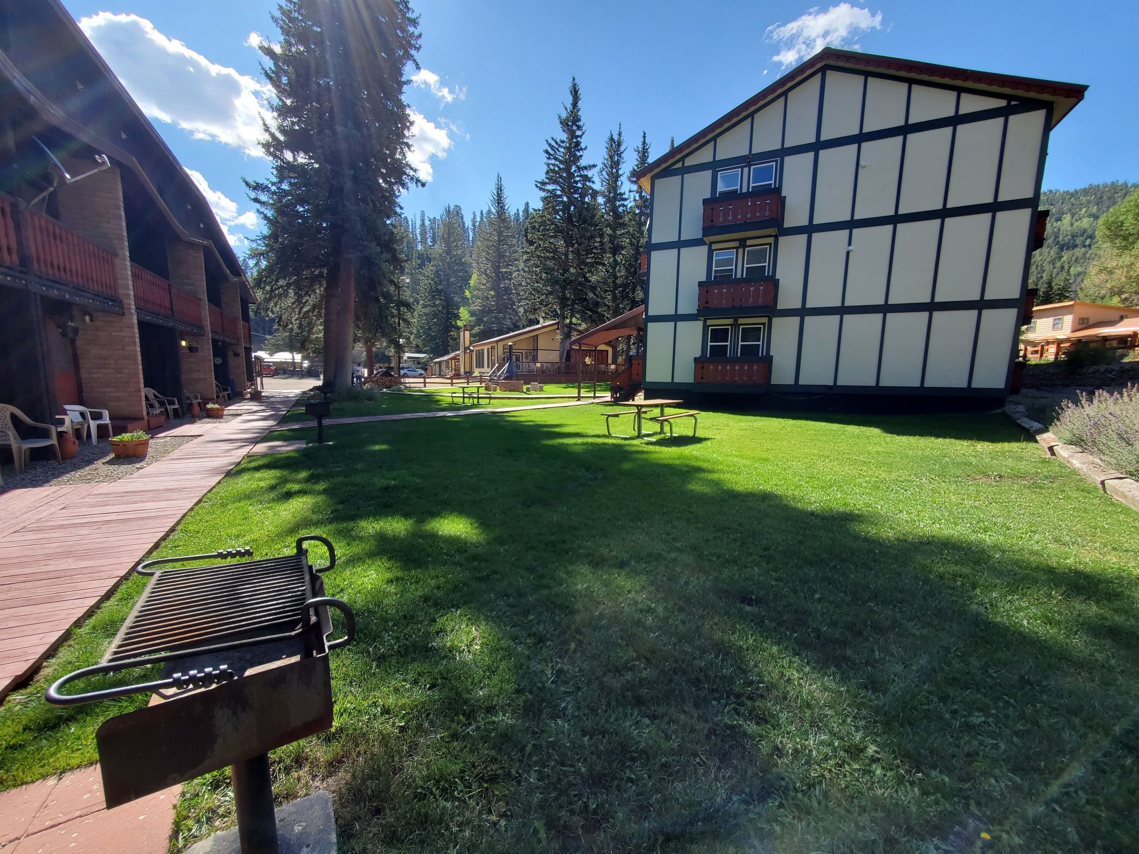 A building with a traditional architectural style, a well-maintained lawn, picnic tables, and a barbecue grill.