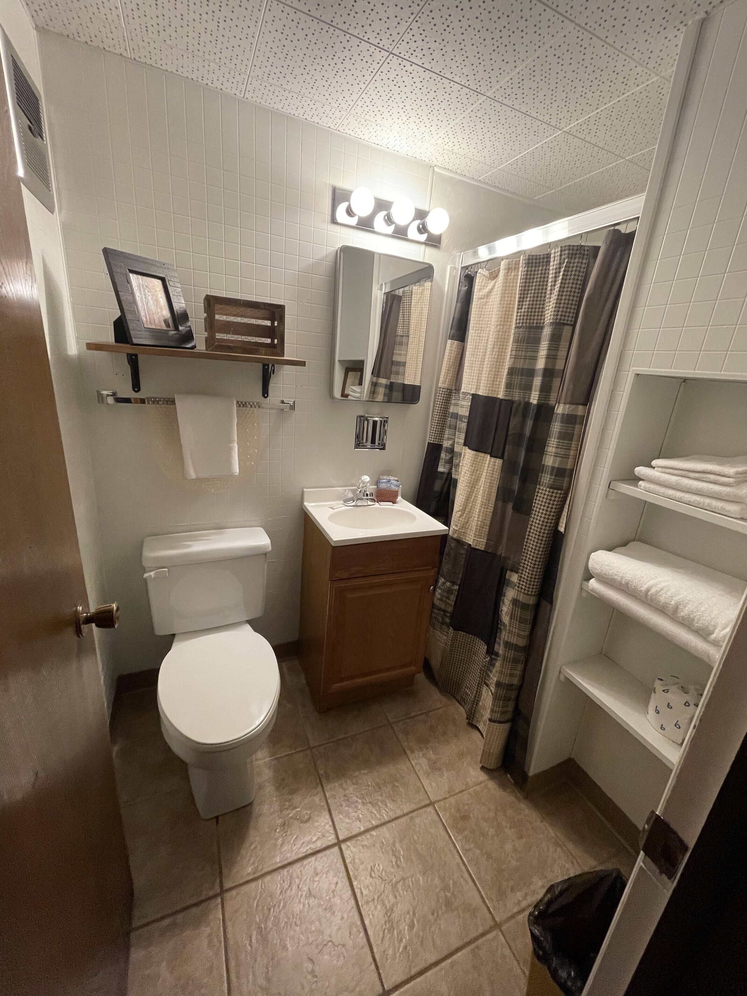 Un baño con inodoro, lavamanos, espejo y toallero.