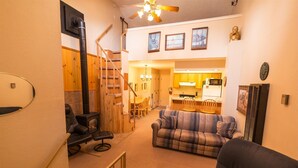 A cozy living room with a fireplace, a sofa, and a dining area with wooden furniture. - Auslander Condominiums (Red River)