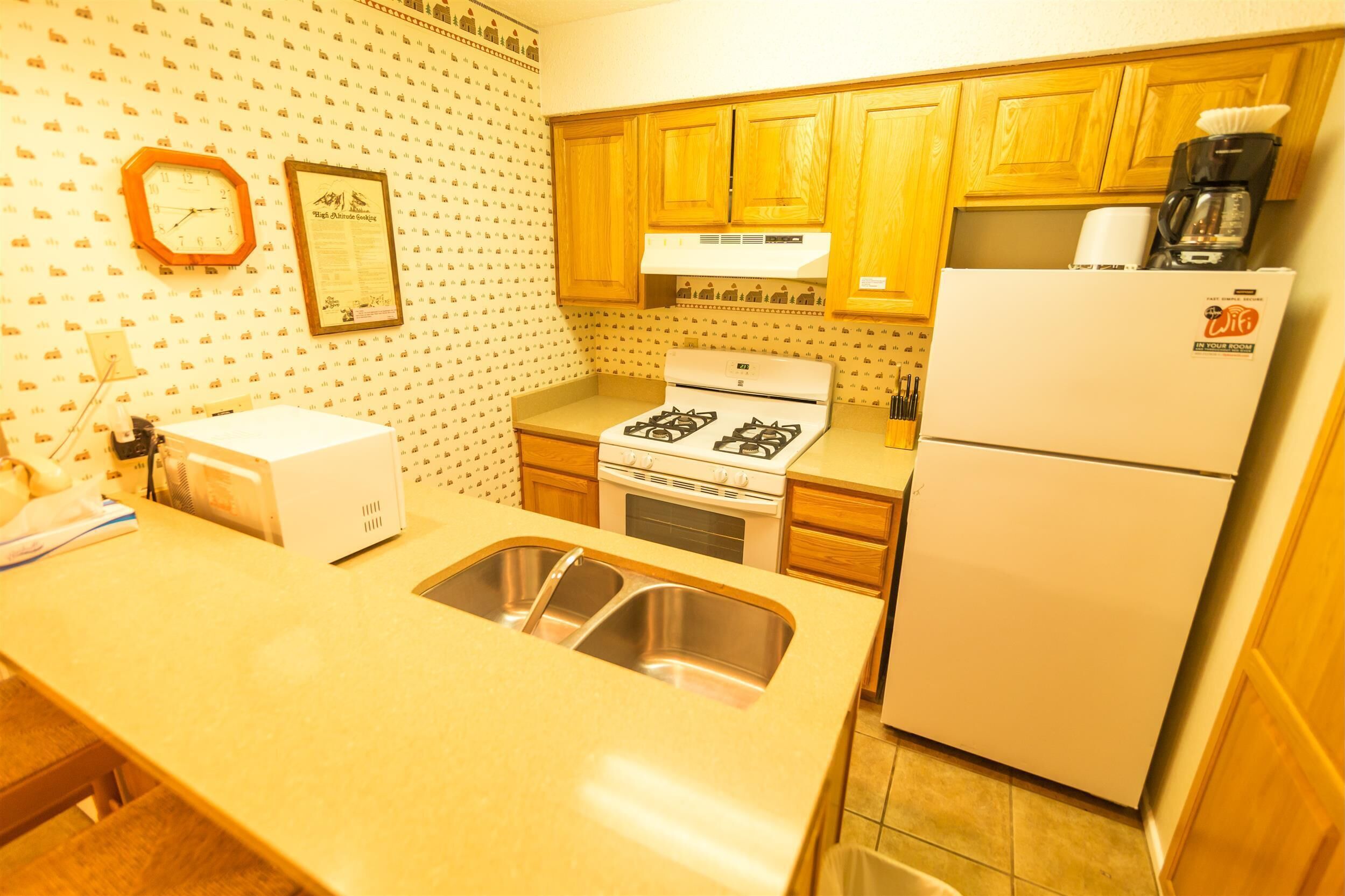 A kitchen with wooden cabinets, a stove, a refrigerator, and a sink.