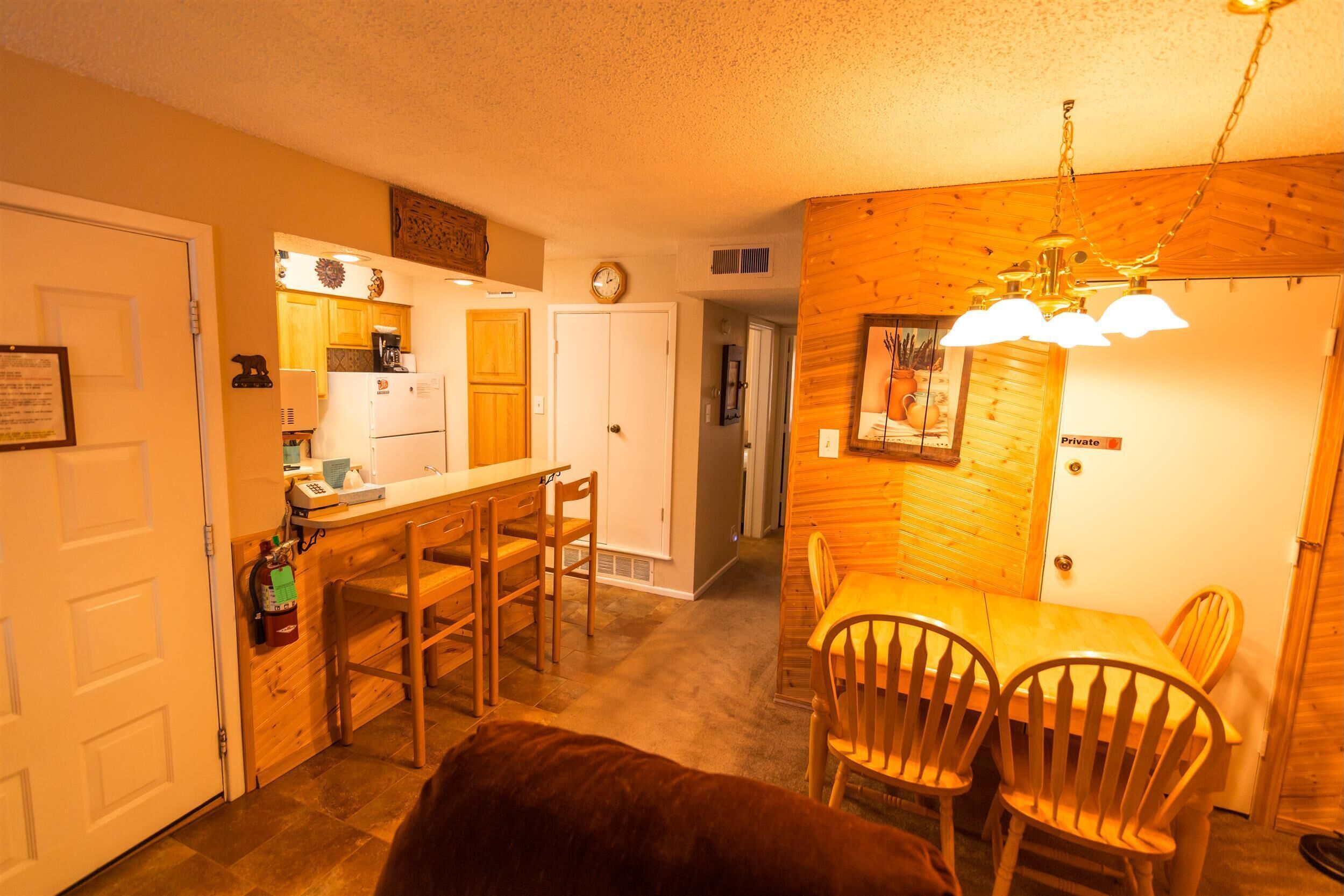 A cozy kitchen with wooden cabinets, a refrigerator, and a dining area with chairs and a table.