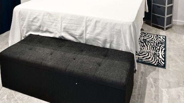 Et moderne soveværelse med en stor seng, et natbord, en lille natlampe, en grå opbevaringsenhed og en måtte med zebra-mønster.
