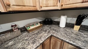 A kitchen with wooden cabinets, a granite countertop, a coffee maker, a toaster, a paper towel holder, and a knife block. - New cute clean 4plex w/game rm, centrally located between North Pole & Fairbanks (Fairbanks)