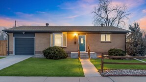 A two-story house with a dark garage door, a front entrance with a light fixture, and a well-maintained lawn.