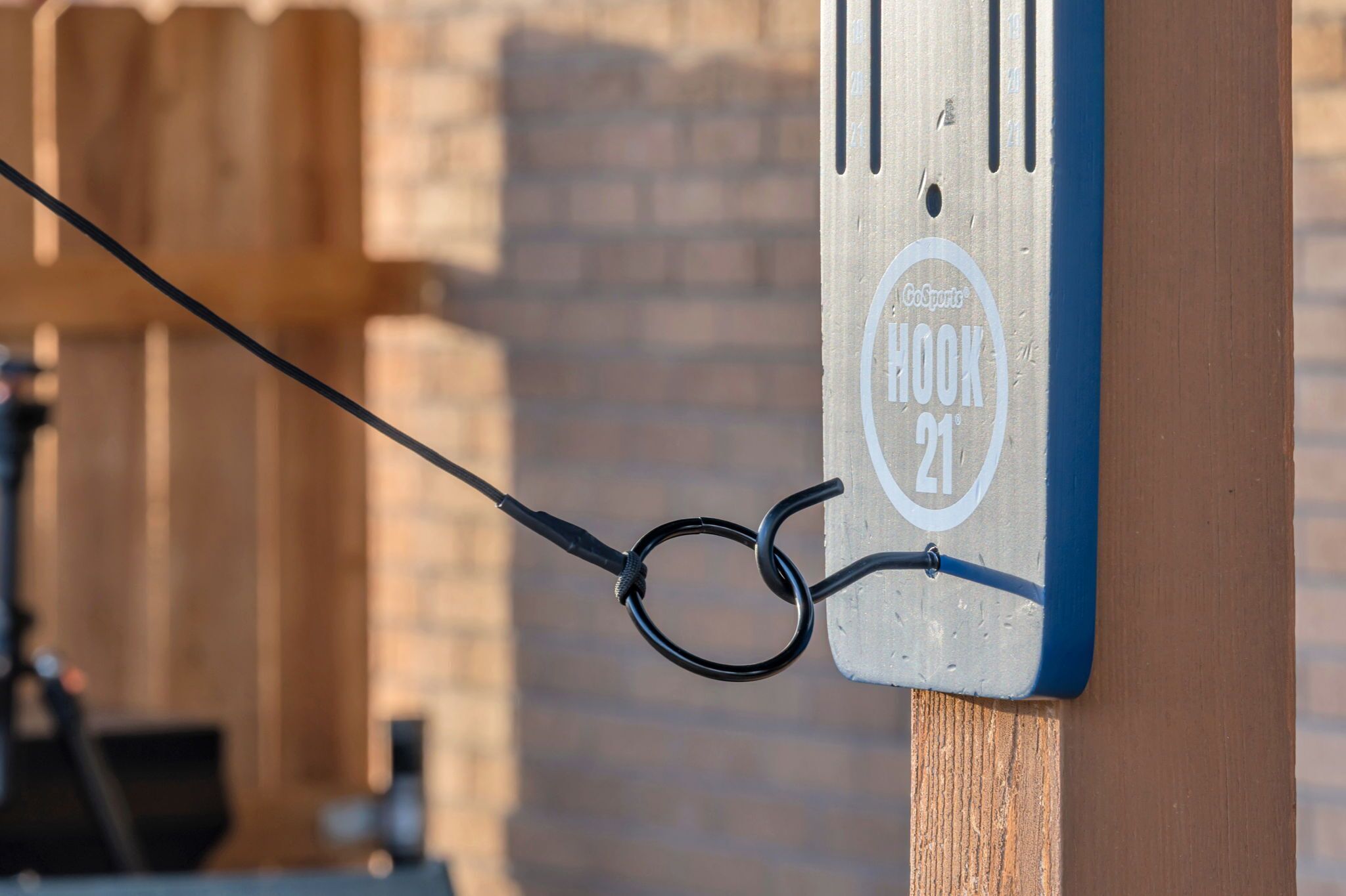 Ein Metallschild mit dem Aufdruck 'GO Sports HOOK 21', befestigt an einem Holzpfosten.