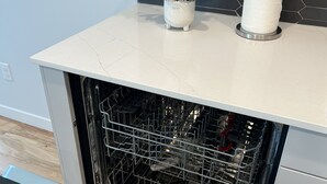 Una cucina moderna con lavastoviglie, un'orchidea bianca in vaso e un porta carta da cucina sul piano di lavoro.