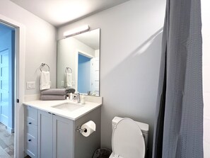 Ein Badezimmer mit Waschbecken, Spiegel, Toilette und Handtuchhalter.