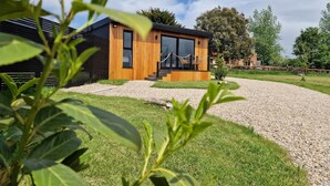 A modern wooden cabin with a gravel driveway and a small garden area. - TT Lodges (Stockton-on-Tees)