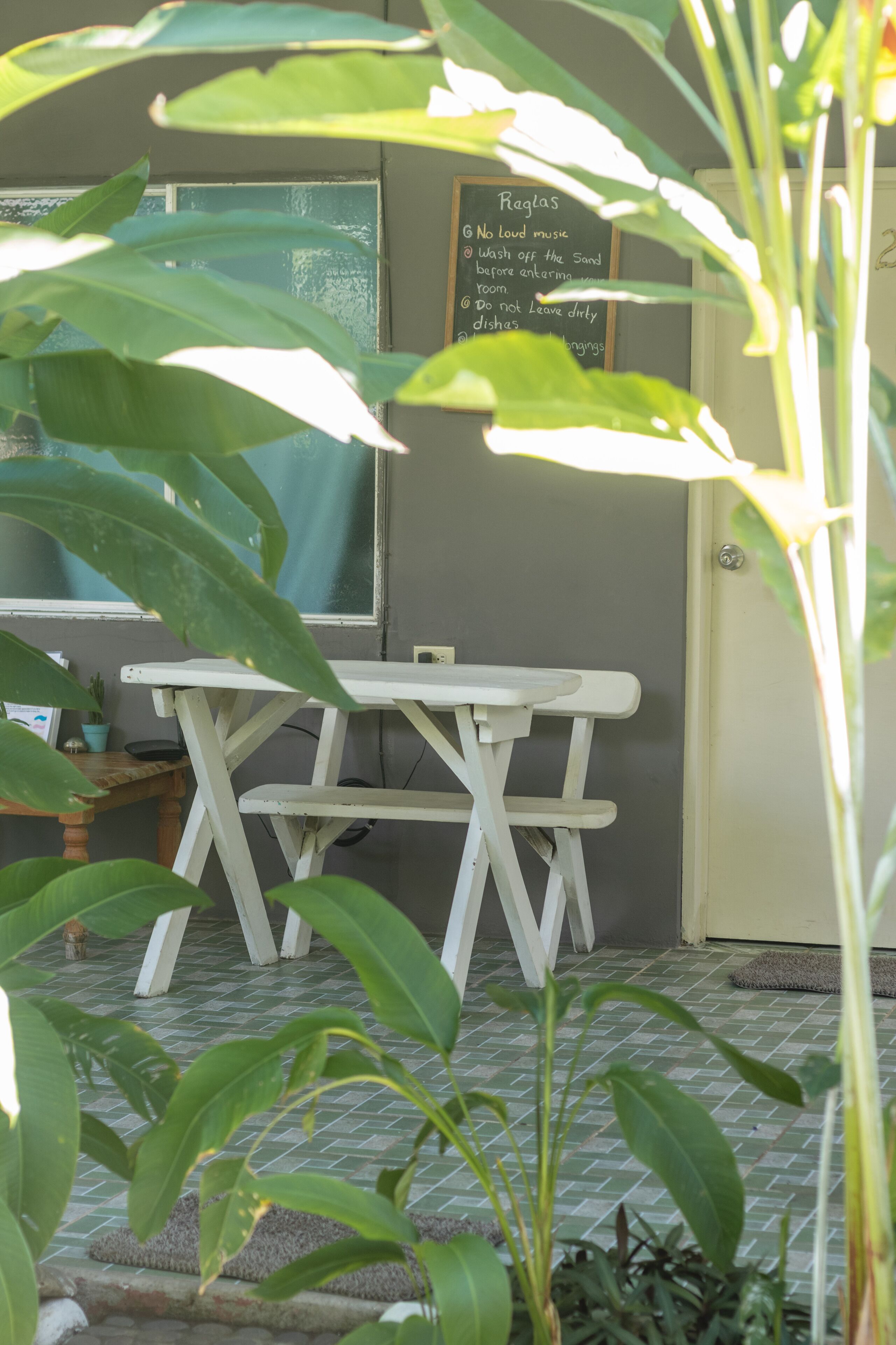 A room with a white table and chairs, a chalkboard with rules, and a window with a view.