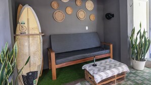 Une pièce avec un banc en bois, une planche de surf et un mur décoré de nattes tissées.