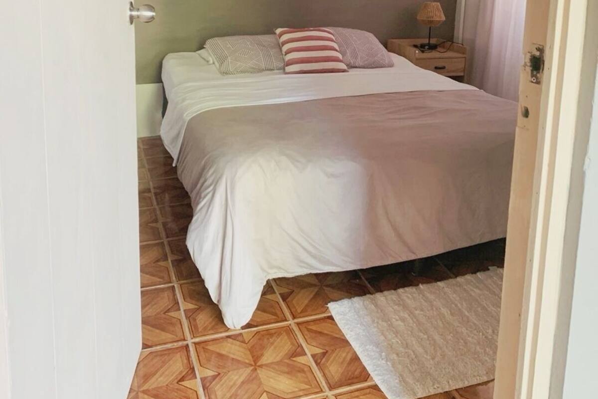 Un dormitorio con cama, mesita de noche, aire acondicionado y suelo estampado.