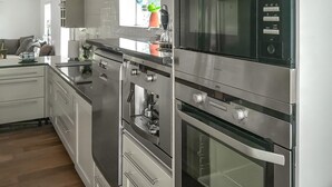 A modern kitchen with stainless steel appliances, including a microwave, oven, and espresso machine. - Nice home in öxnevalla (Öxnevalla)