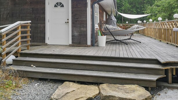 A wooden deck with a hammock, a white door, and a small porch area. - Nice home in öxnevalla (Öxnevalla)