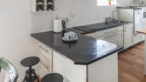 A modern kitchen with white cabinets, a black countertop, and a built-in sink. - Nice home in öxnevalla (Öxnevalla)