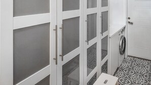 A laundry room with a washing machine, a small table, and a cabinet with frosted glass doors. - Nice home in öxnevalla (Öxnevalla)