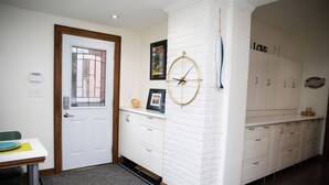 A hallway with a white door, a framed picture, a clock, and a cabinet with drawers. - Charming historic home w/ parking, walk to downtown, waterfront, shops & more. (North Bay)