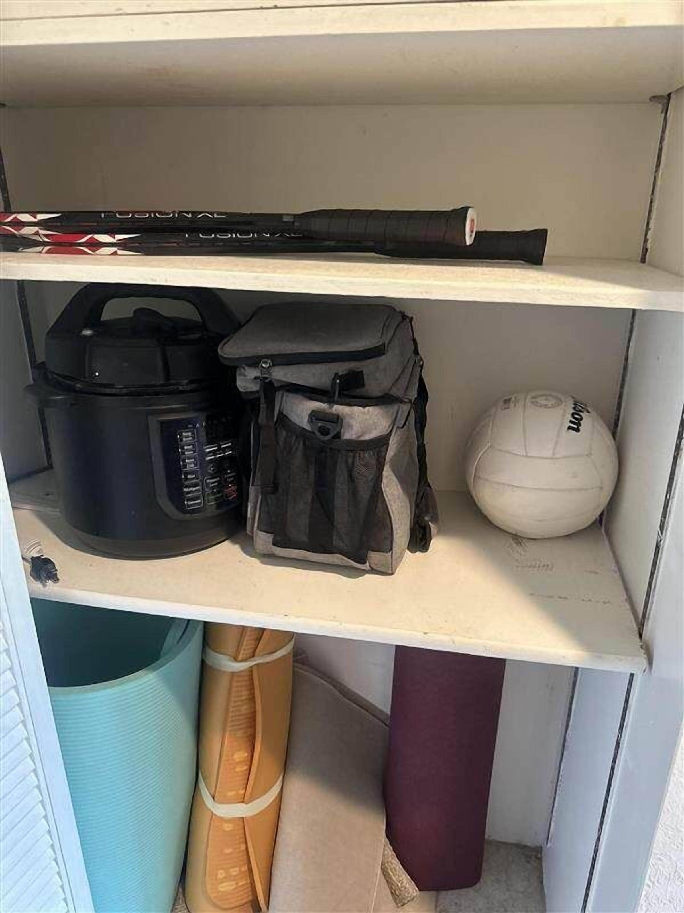 Ein Regal mit einem schwarzen Koffer, einem grauen Rucksack und einem weißen Helm.