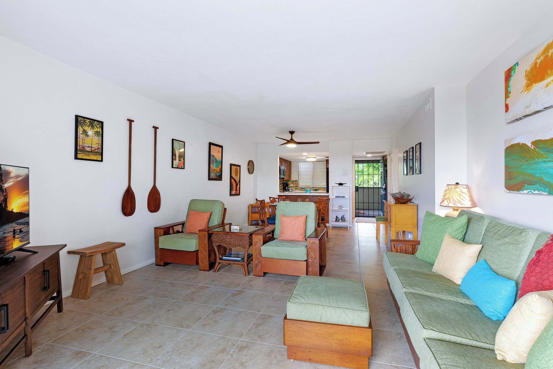 A spacious living area with a sofa, chairs, a wooden table, and a television.