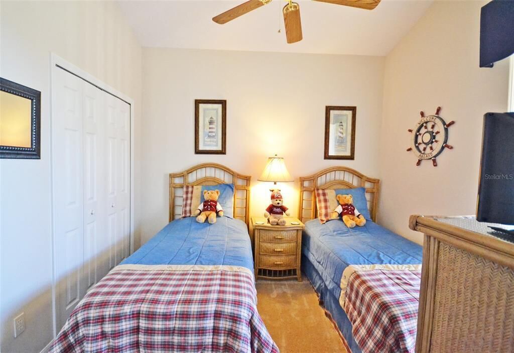 Een slaapkamer met twee bedden, een plafondventilator, een lamp en een decoratie van een scheepsschroef.
