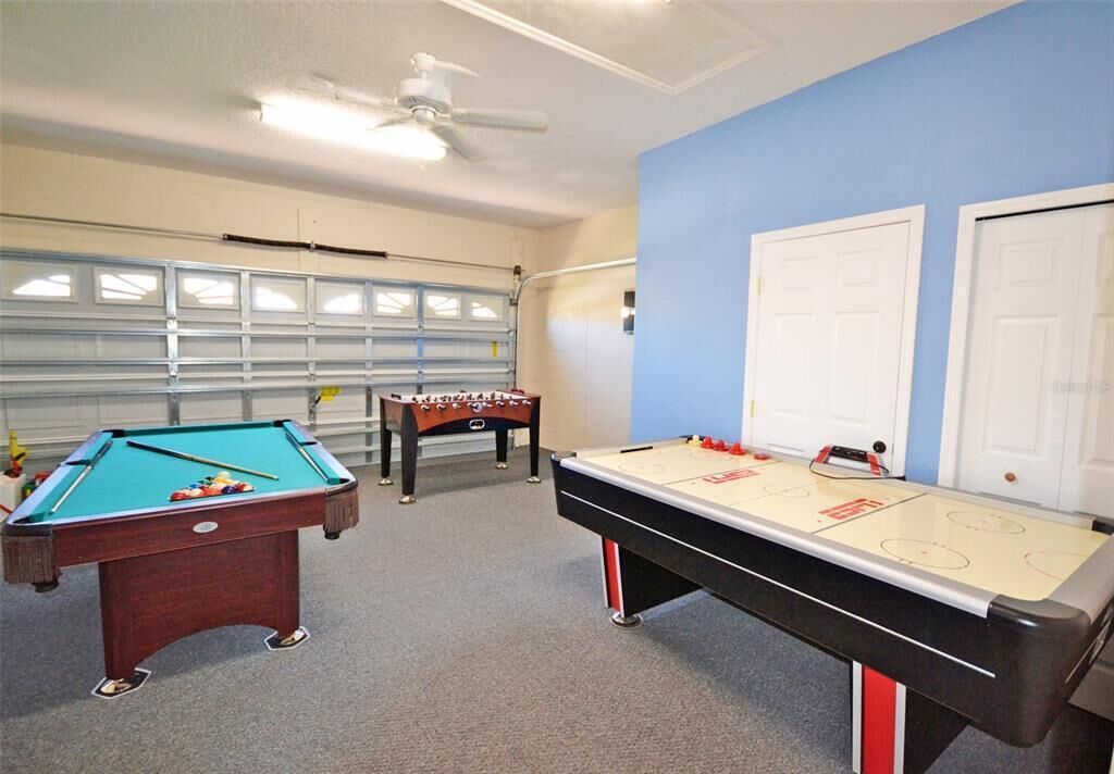 A recreational room with a pool table, foosball table, and shuffleboard table.