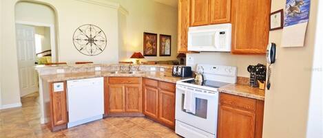 A kitchen with wooden cabinets, a white dishwasher, a stove, and a microwave.