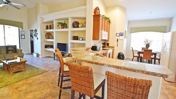 Una cocina moderna con barra, sillas de mimbre y una mesa de comedor.