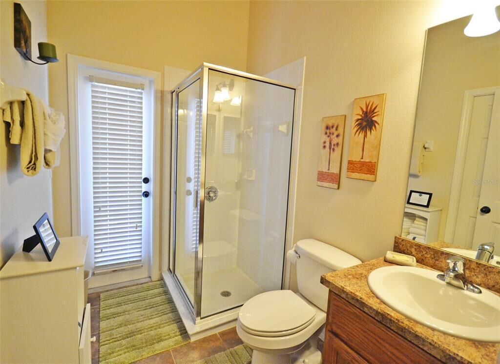 A bathroom with a glass-enclosed shower, a toilet, a sink, and a mirror.