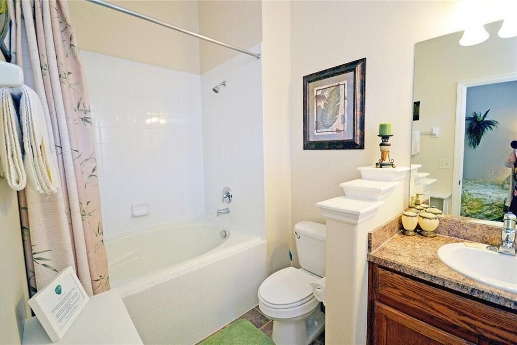 Un baño con bañera, inodoro y tocador con lavamanos.