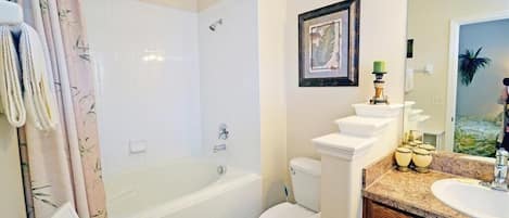 Un baño con bañera, inodoro y tocador con lavamanos.