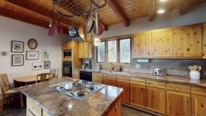 Une cuisine avec des meubles en bois, un plan de travail en granit et des casseroles suspendues.