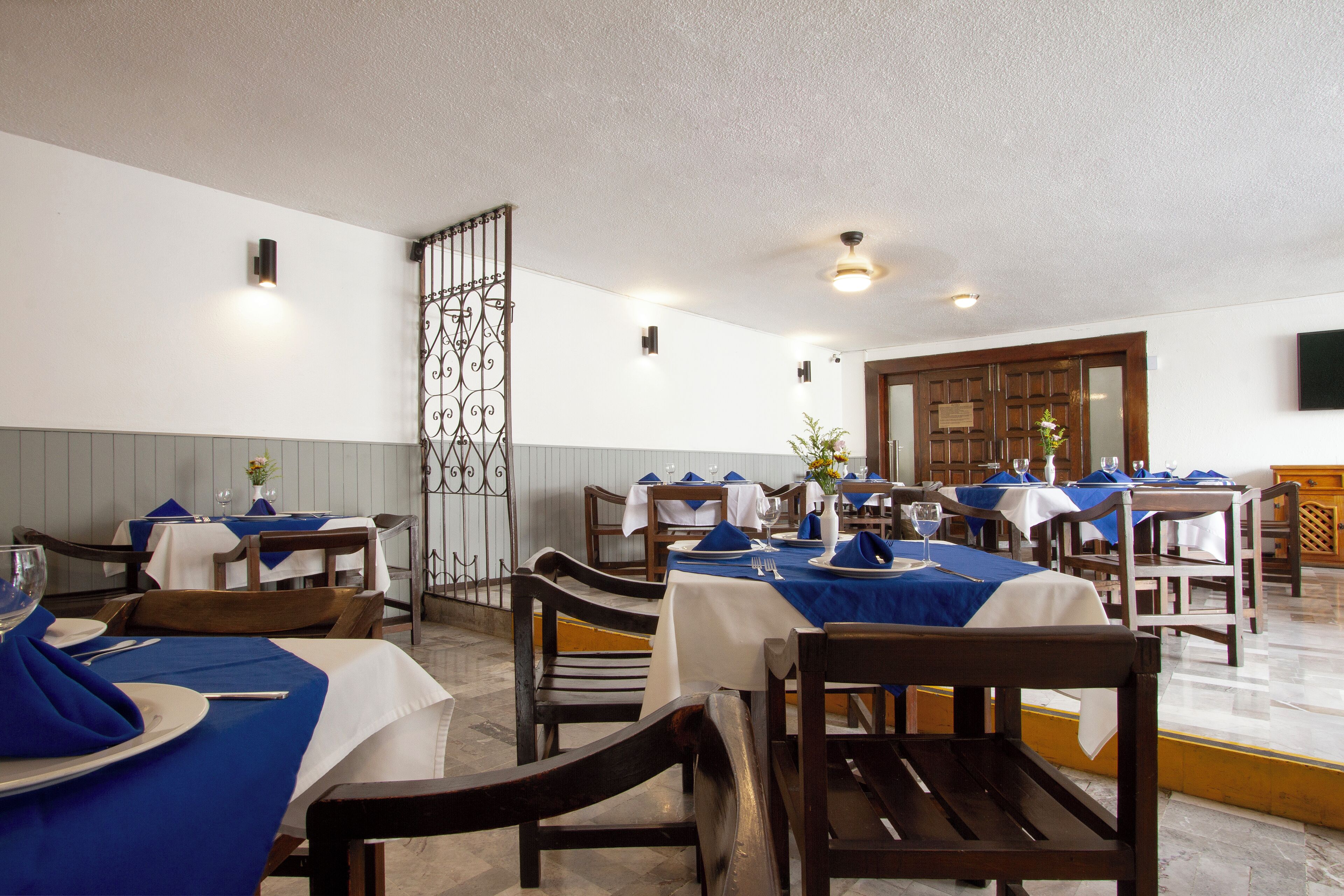 A restaurant with tables set for dining, featuring blue tablecloths and white napkins.