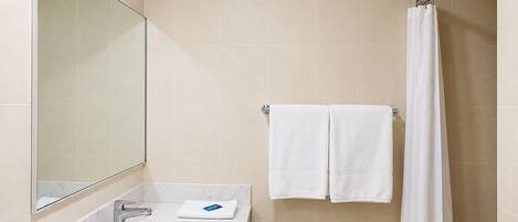 Une salle de bain équipée d’un lavabo, d’un miroir, d’un porte-serviettes et d’un rideau de douche.