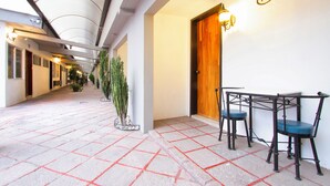 A corridor with a tiled floor, a wooden door, and two chairs. - Hotel Bedd Express Querétaro (Querétaro)