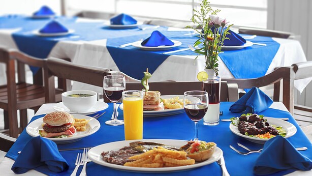 A dining table set with blue tablecloths, plates of food, and drinks. - Hotel Bedd Express Querétaro (Querétaro)