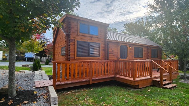 Een houten blokhut met een terras en een overdekte veranda.