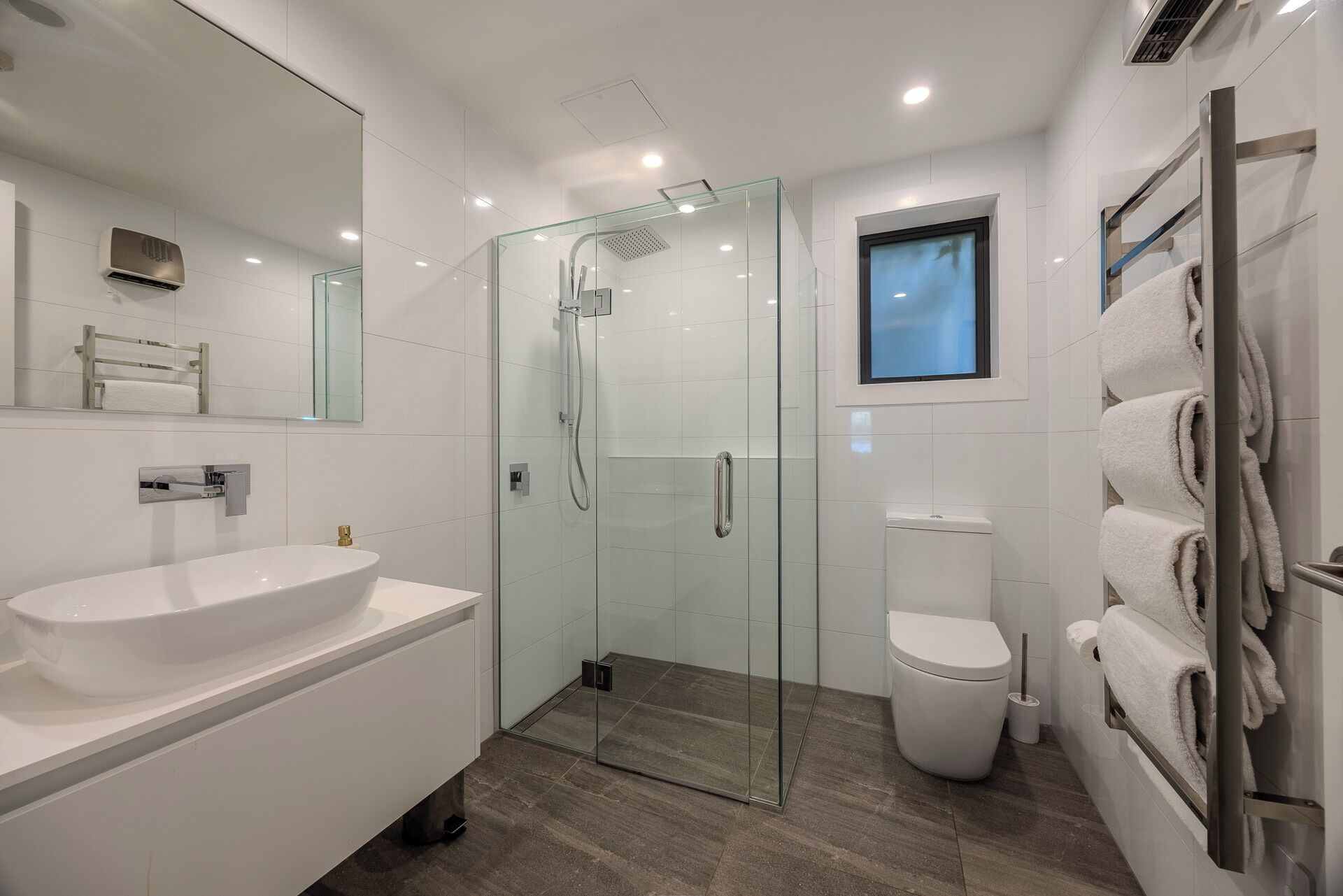 Une salle de bain moderne avec une douche à parois de verre, un lavabo blanc et des toilettes.