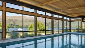 An indoor swimming pool with large windows offering views of mountains and a lake. - Marina Terrace Apartments (Wanaka)