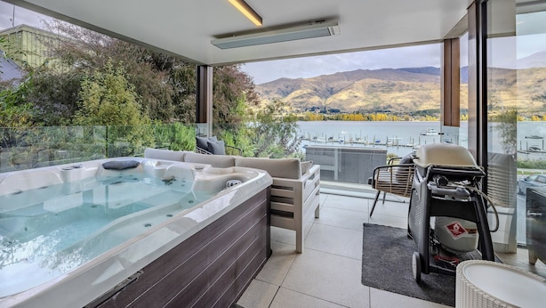 A modern outdoor hot tub area with a view of a lake and mountains. - Marina Terrace Apartments (Wanaka)