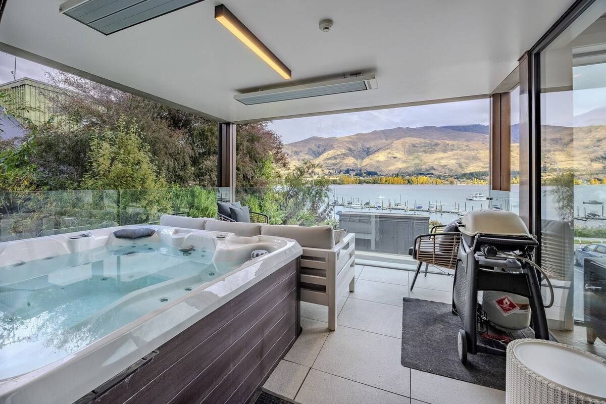 A modern outdoor hot tub area with a view of a lake and mountains.