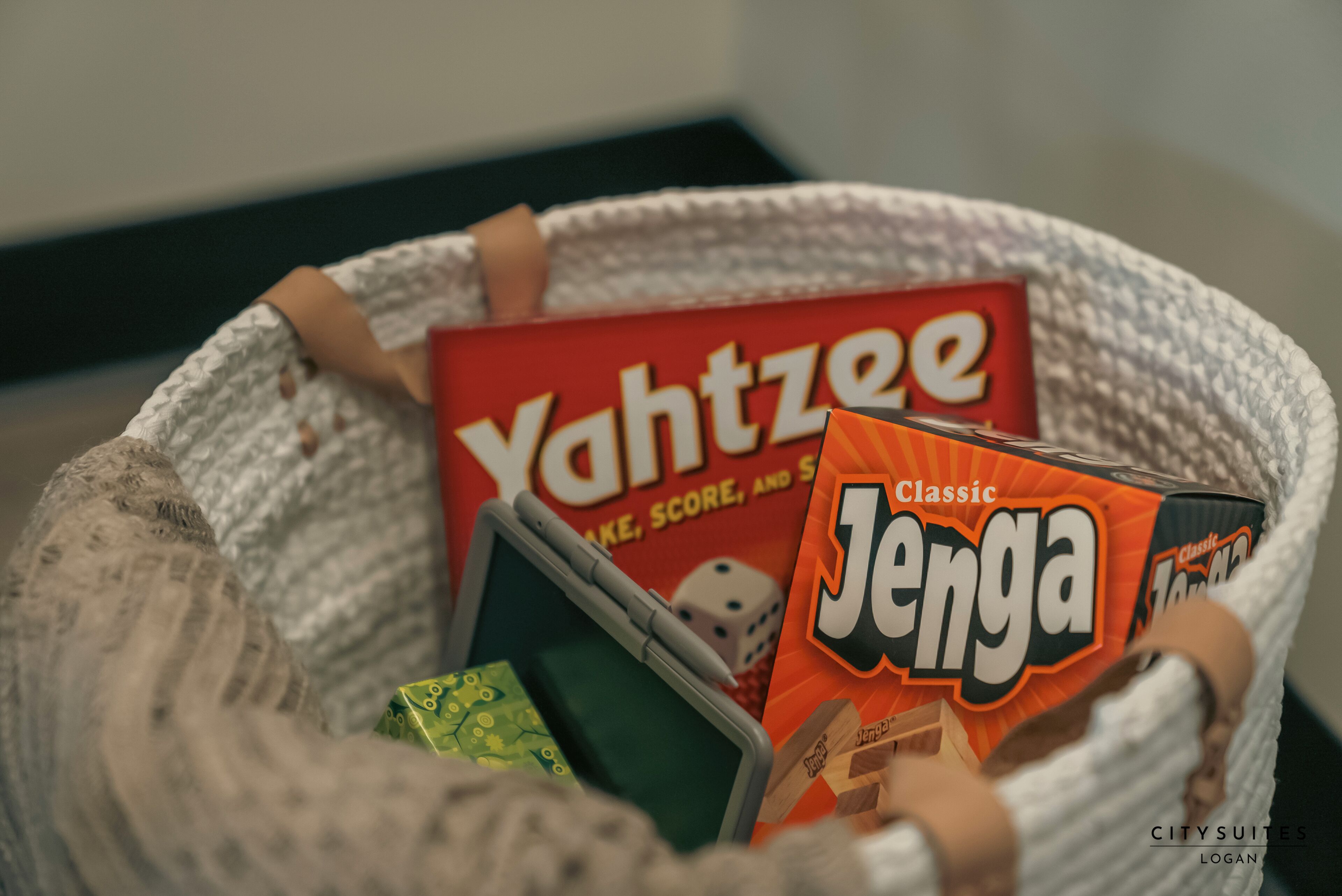 Een mand met gezelschapsspellen, waaronder 'Yachtzee' en 'Jenga'.
