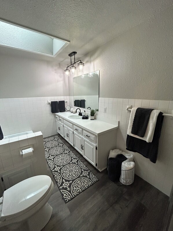 A modern bathroom with a white vanity, a large mirror, and a patterned rug.