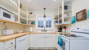 A kitchen with white cabinets, a wooden countertop, a microwave, a sink, and a stove.
