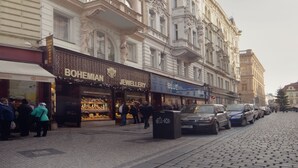 Um edifício histórico com arquitetura ornamentada, com lojas no andar térreo.
