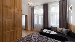 Quarto com cama, sofá, guarda-roupa de madeira e um candelabro.