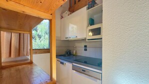 A compact kitchen with white cabinets, a stainless steel sink, and a wooden countertop.