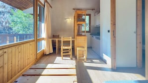 A wooden interior with a dining area, kitchen, and large windows.