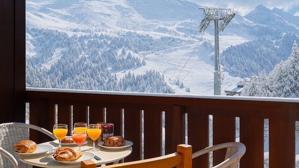 A dining table with breakfast items and a mountain view.
